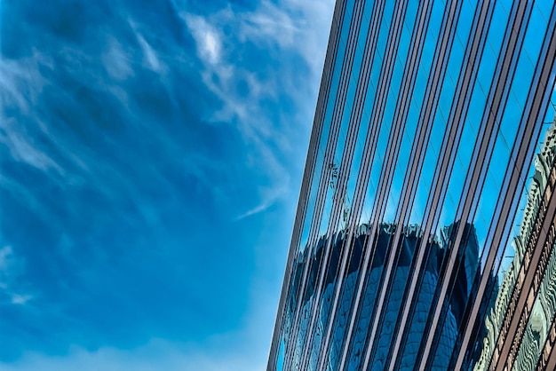 Low angle shot of a tall glass building under a blue cloudy sky