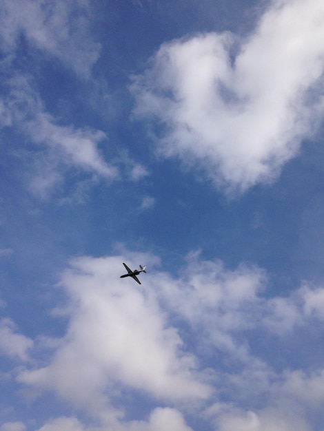 Low angle view of airplane flying in cloudy sky