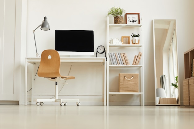 Low angle view at all-white modern interior with focus on empty home office workplace