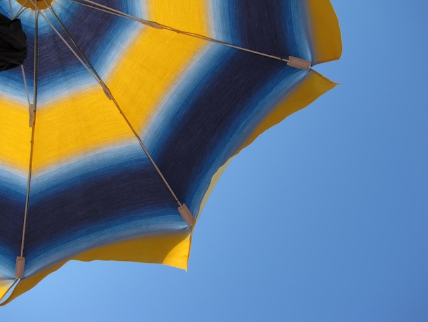 Low angle view of beach umbrella against clear blue sky