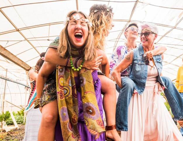 Low angle view of cheerful women piggybacking female friends in greenhouse