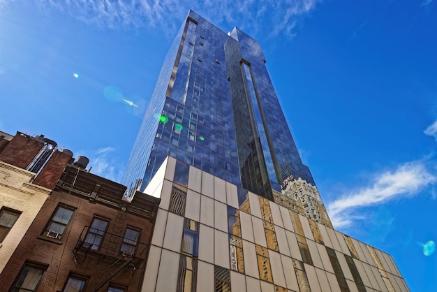 Low angle view of a contemporary glass and steel office skyscraper reflecting the clear blue sky above in New York City, USA