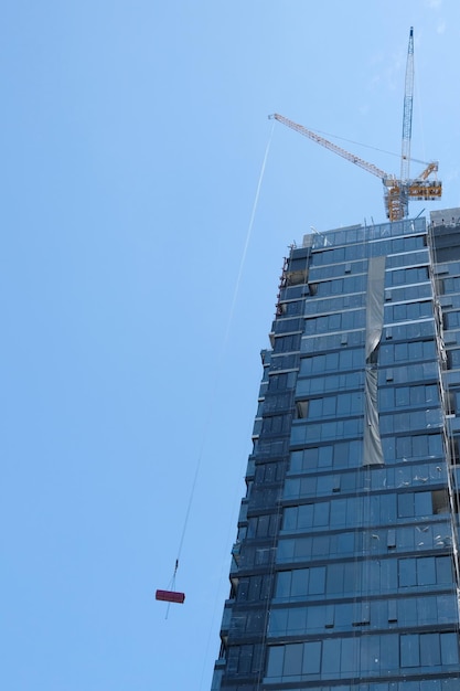 Photo low angle view of crane by building against clear blue sky