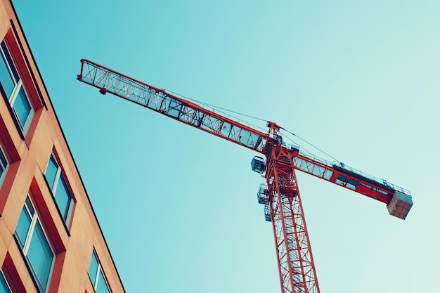 Low angle view of crane by building against clear sky