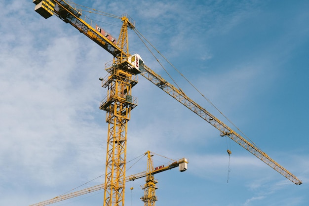 Low angle view of cranes at construction site against sky