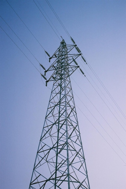 Low angle view of electricity pylon against clear blue sky