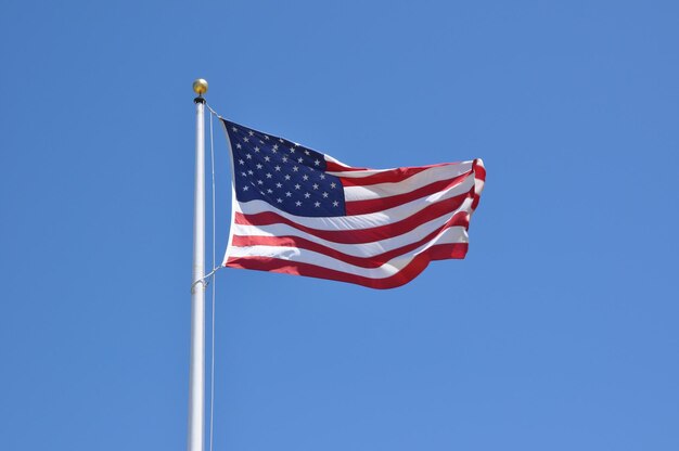 Low angle view of flag against clear blue sky