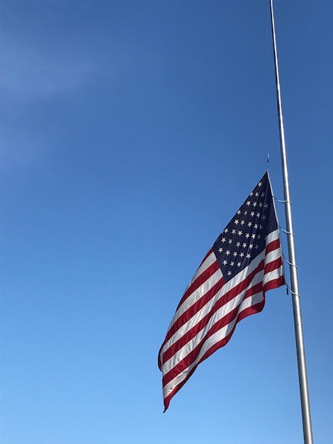 Low angle view of flag against clear blue sky