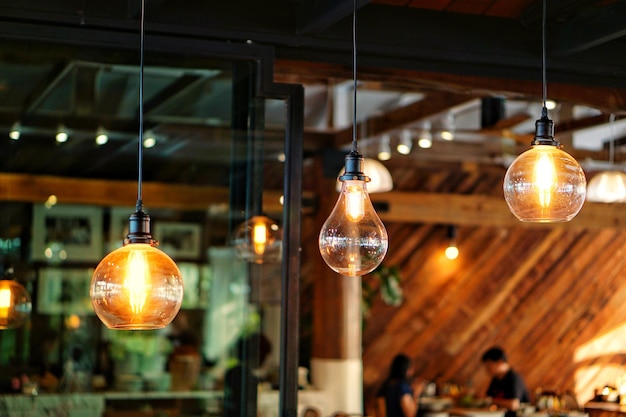 Photo low angle view of illuminated light bulbs hanging at restaurant