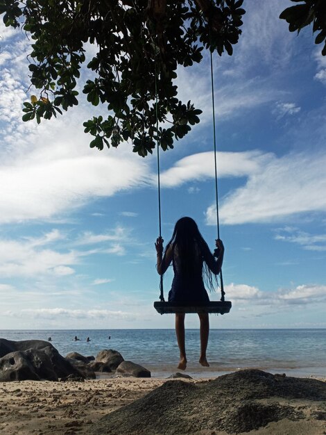 Photo low angle view of man swinging at beach against sky