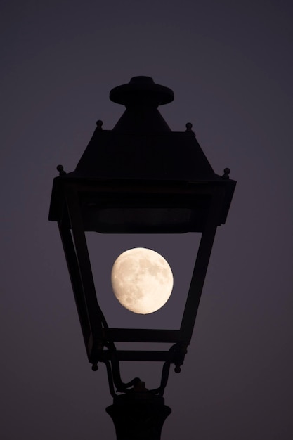 Photo low angle view of moon seen through silhouette lantern against sky