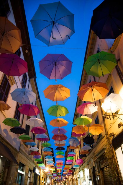 Low angle view of multi colored umbrellas hanging against sky