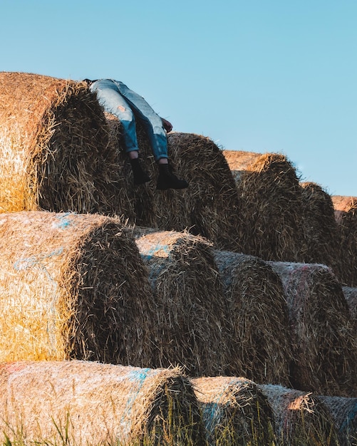 Photo low angle view of person lying on hay bales against clear sky