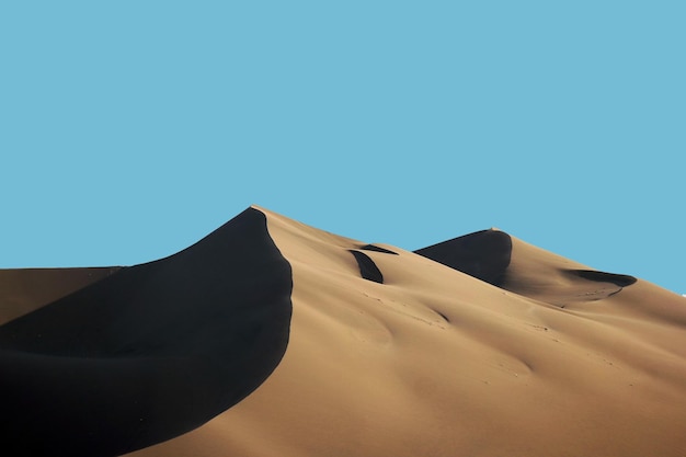 Low angle view of sand dunes against clear blue sky