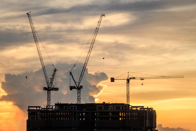 Low angle view of silhouette cranes against sky during sunset