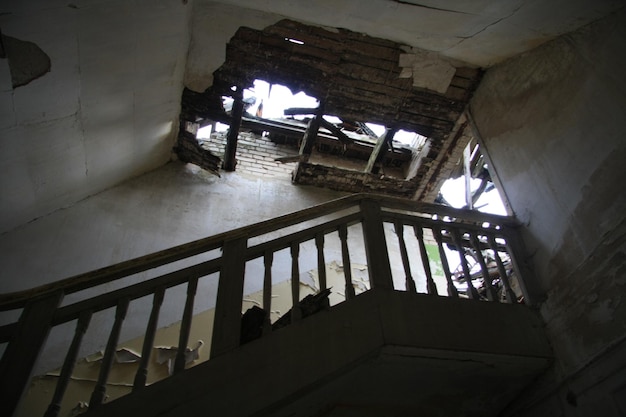 Low angle view of steps and broken ceiling in abandoned house