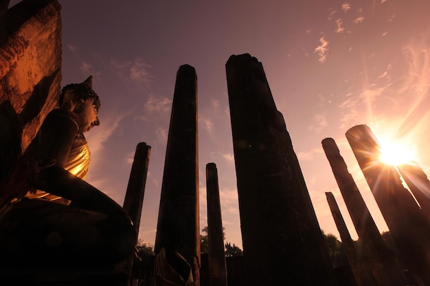 Low angle view of sun shining through religious monuments