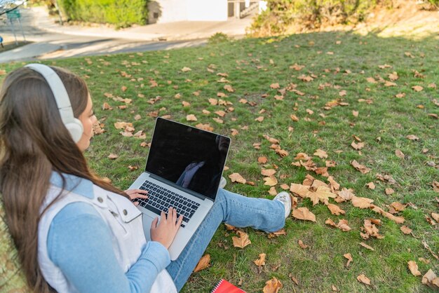 low angle view of a teenage girl using her computer sitting on a tree with her supplies next to her