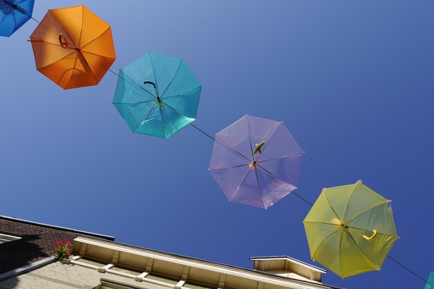 Low angle view of umbrellas against clear blue sky