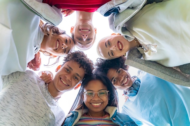 Low angle view of young trendy friends hugging smiling and making a circle with their heads