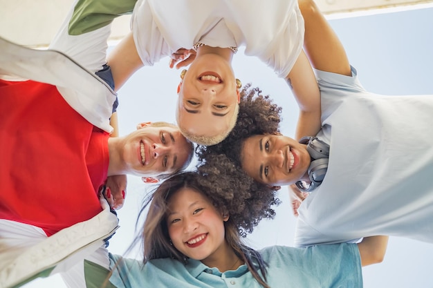 Low angle view of young trendy friends hugging smiling and making a circle with their heads