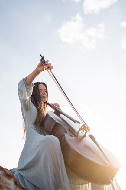 Low angle of woman playing cello with copy space