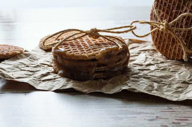 Low key photography. Closeup of a stack of stroopwafels with a sisal bow, next to other cookies.