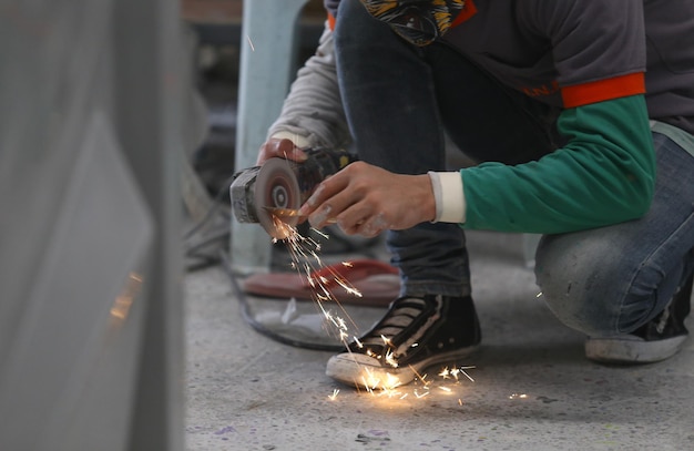 Photo low section of man cutting metal in factory