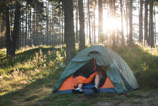 Low section of man sitting in tent at forest