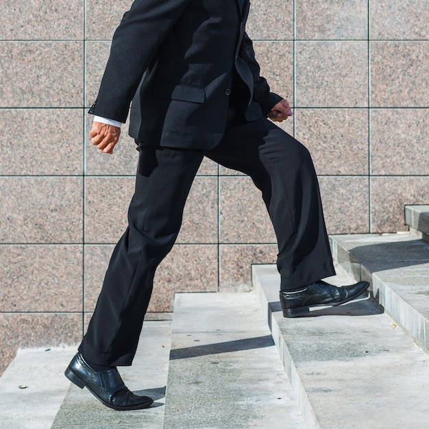 Low section view of a businessman climbing staircase