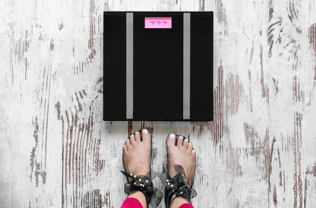 Photo low section of woman standing on wooden floor by weight scale at home