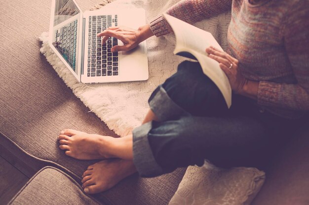 Low section of woman using laptop on sofa at home