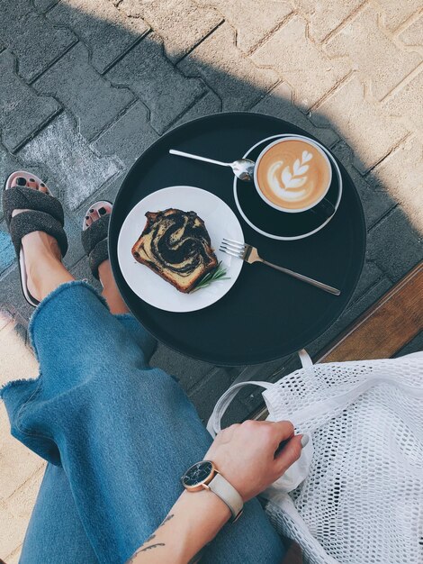 Photo low section of woman with coffee cup and dessert