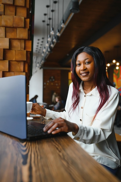 Lucky day Emotional black woman looking at laptop clenching fists and screaming working at cafe copy space