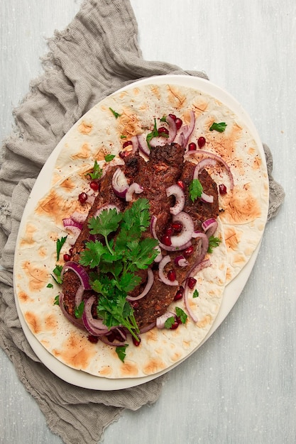 Lula kebab on lavash with red onion pomegranate and sumac top view closeup horizontal no people