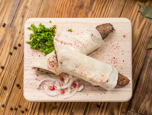 Lula kebab with herbs on a wooden surface