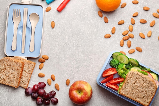 Lunch box with delicious food fruits and almond on light textured background