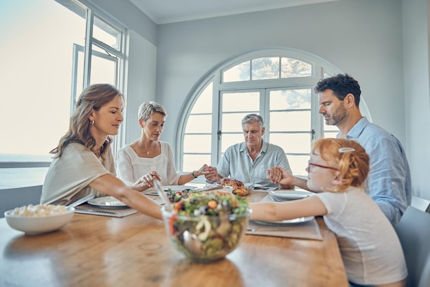 Lunch praying and family together at dining room table in home Grandparents child and parent teaching grace or spiritual religion prayer respect to kid before dinner in religious retirement house