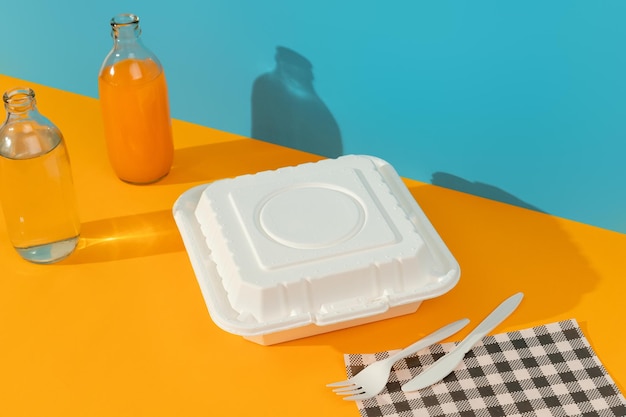 Lunchboxes cutlery and drinks on orange table food delivery concept