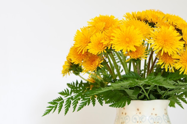 Lush bouquet of fluffy yellow dandelions in a vase of pastel colors