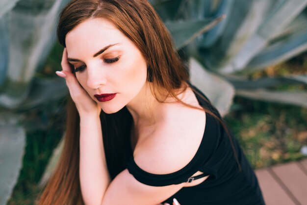 A luxurious attractive young woman in a dress resting in the garden, a rich life