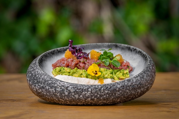 Luxurious tuna tartare with salad and herbs Wooden table