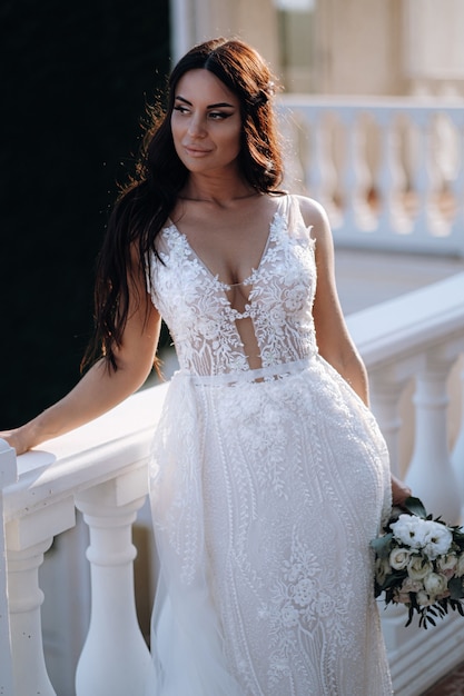 Luxurious young bride in an expensive fashionable wardrobe poses for a wedding photo shoot in a luxury resort town