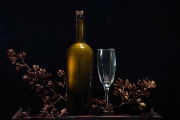 luxury bottle wine and dry flowers on black background