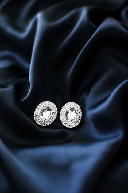 Luxury diamond earrings on dark blue silk background holiday glamour jewelery present