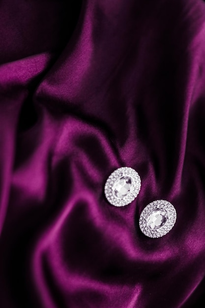 Luxury diamond earrings on dark pink silk fabric holiday glamour jewelery present