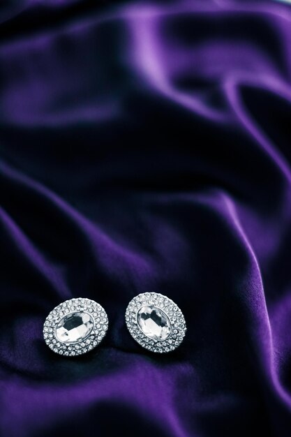 Luxury diamond earrings on dark violet silk fabric holiday glamour jewelery present