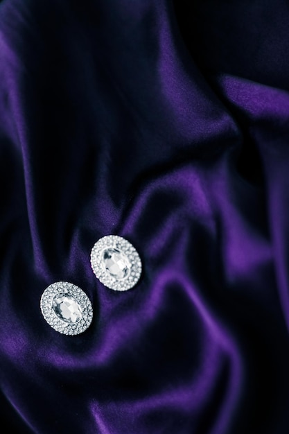 Luxury diamond earrings on dark violet silk fabric holiday glamour jewelery present