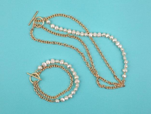 Luxury elegant baroque pearl necklace and bracelet on bright turquoise textured background. Close-up shot