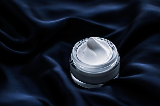 Luxury face cream jar on a dark blue silk